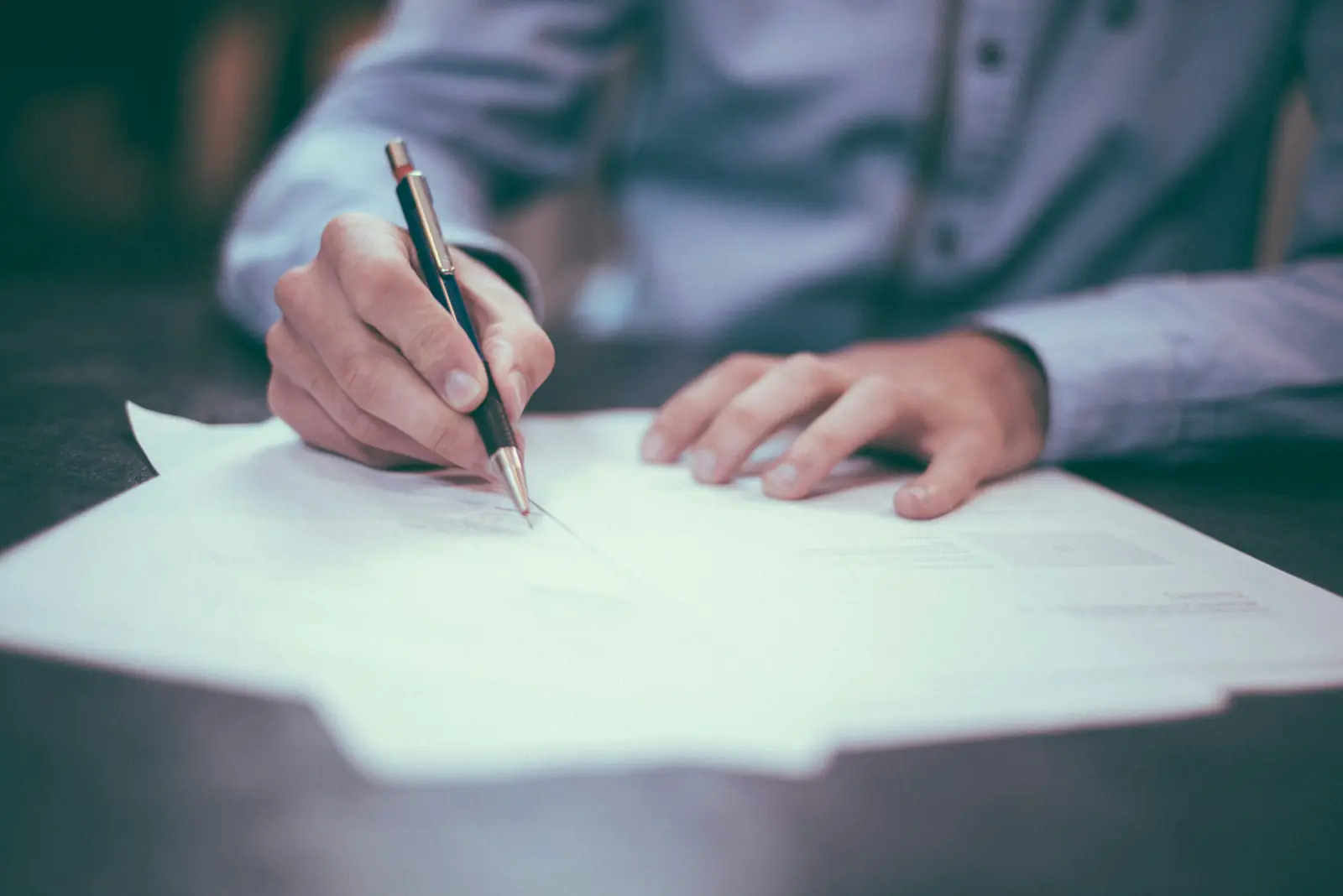 Hände eines Mannes, der mit einem Stift auf Papier schreibt