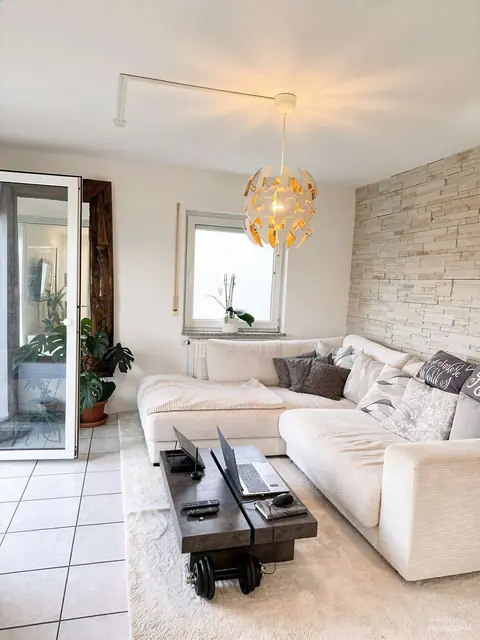 Wohnzimmer im Erdgeschoss mit hellem Ecksofa, mit KI bearbeitet